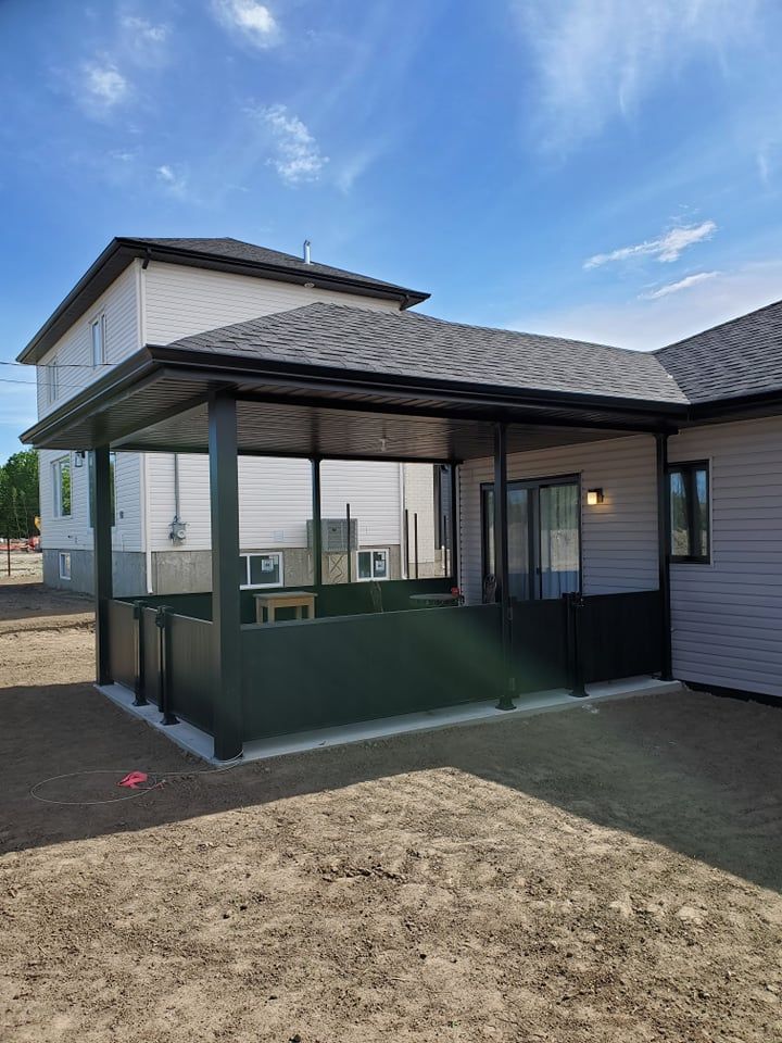 Une maison avec un patio couvert devant elle.