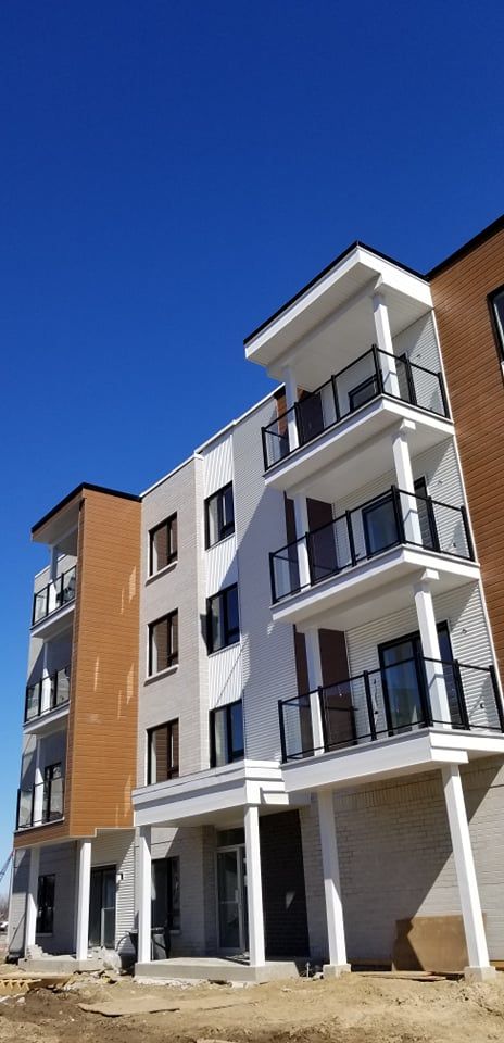 Un grand immeuble d'appartements en construction avec des balcons et un ciel bleu en arrière-plan.