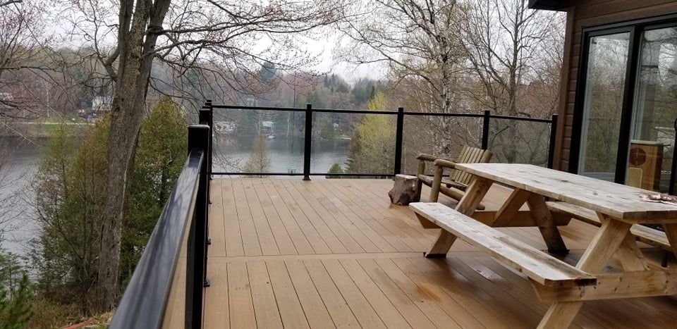Une terrasse en bois avec une table de pique-nique et des bancs donnant sur un lac.
