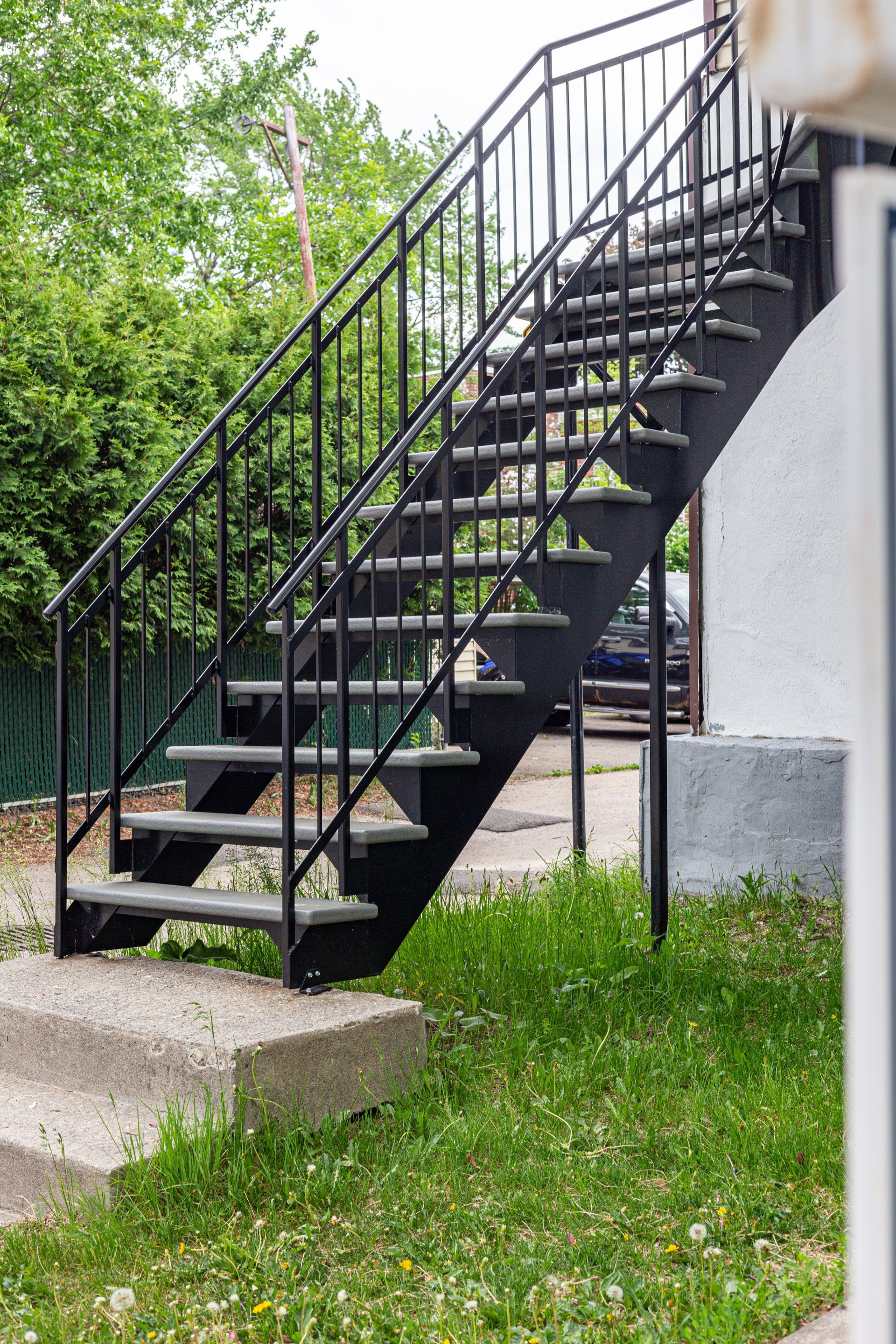 Un ensemble d'escaliers noirs avec une rampe en métal menant à un bâtiment.