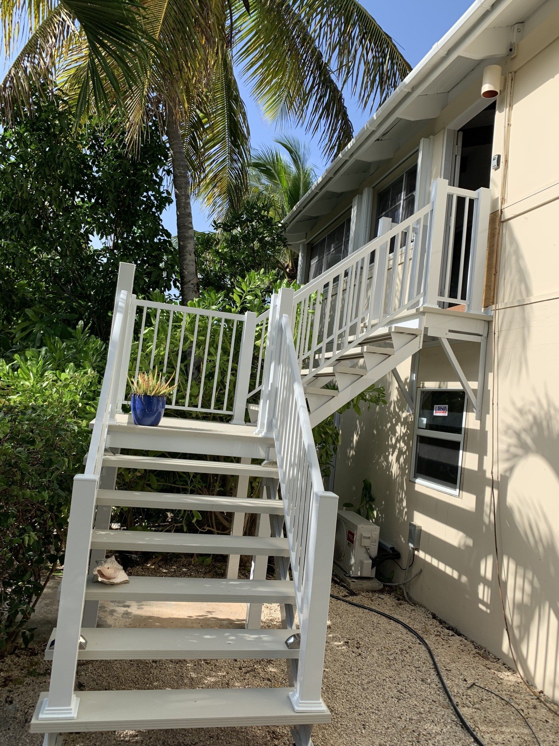 Un escalier blanc menant à un balcon sur le côté d'une maison.