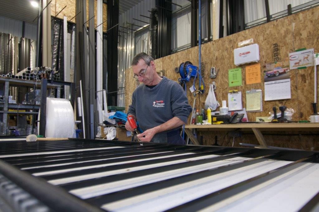 Un homme travaille sur une structure métallique noire et blanche dans un atelier.