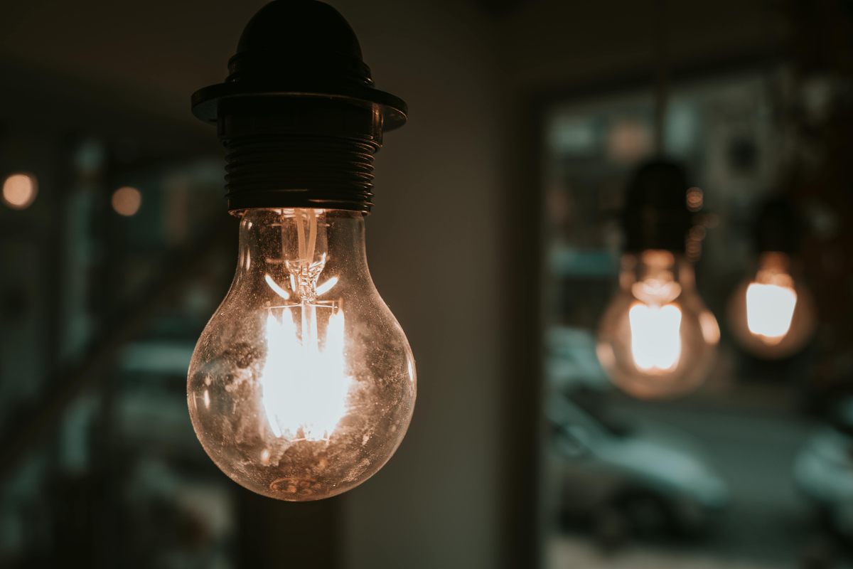 Warm glowing light bulb in focus with blurred hanging bulbs in a dim room