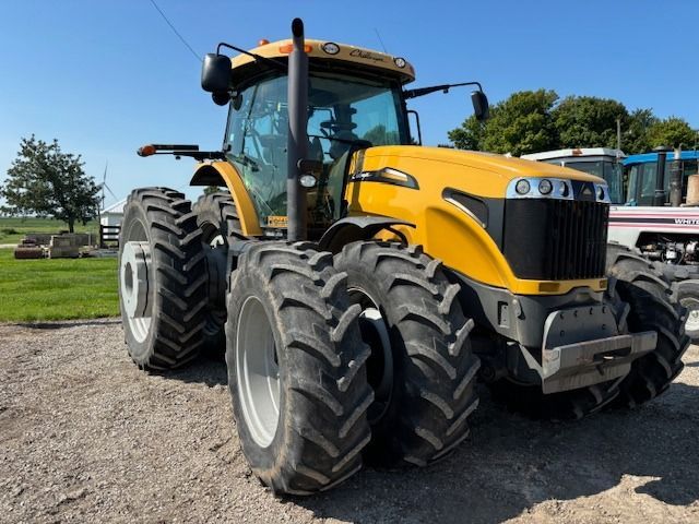 A yellow tractor is parked on a dirt road