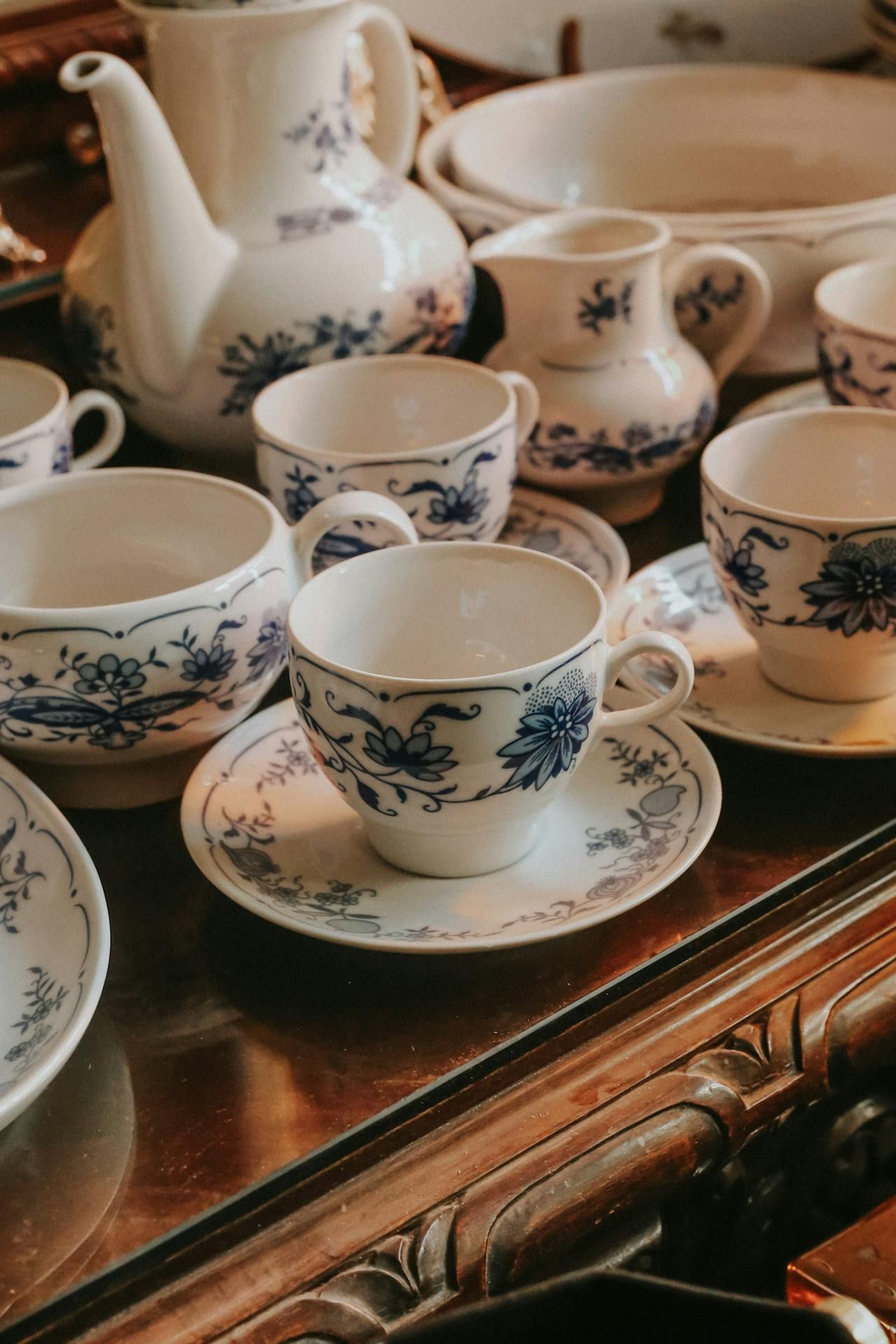 A tea set is sitting on a table in front of a mirror.