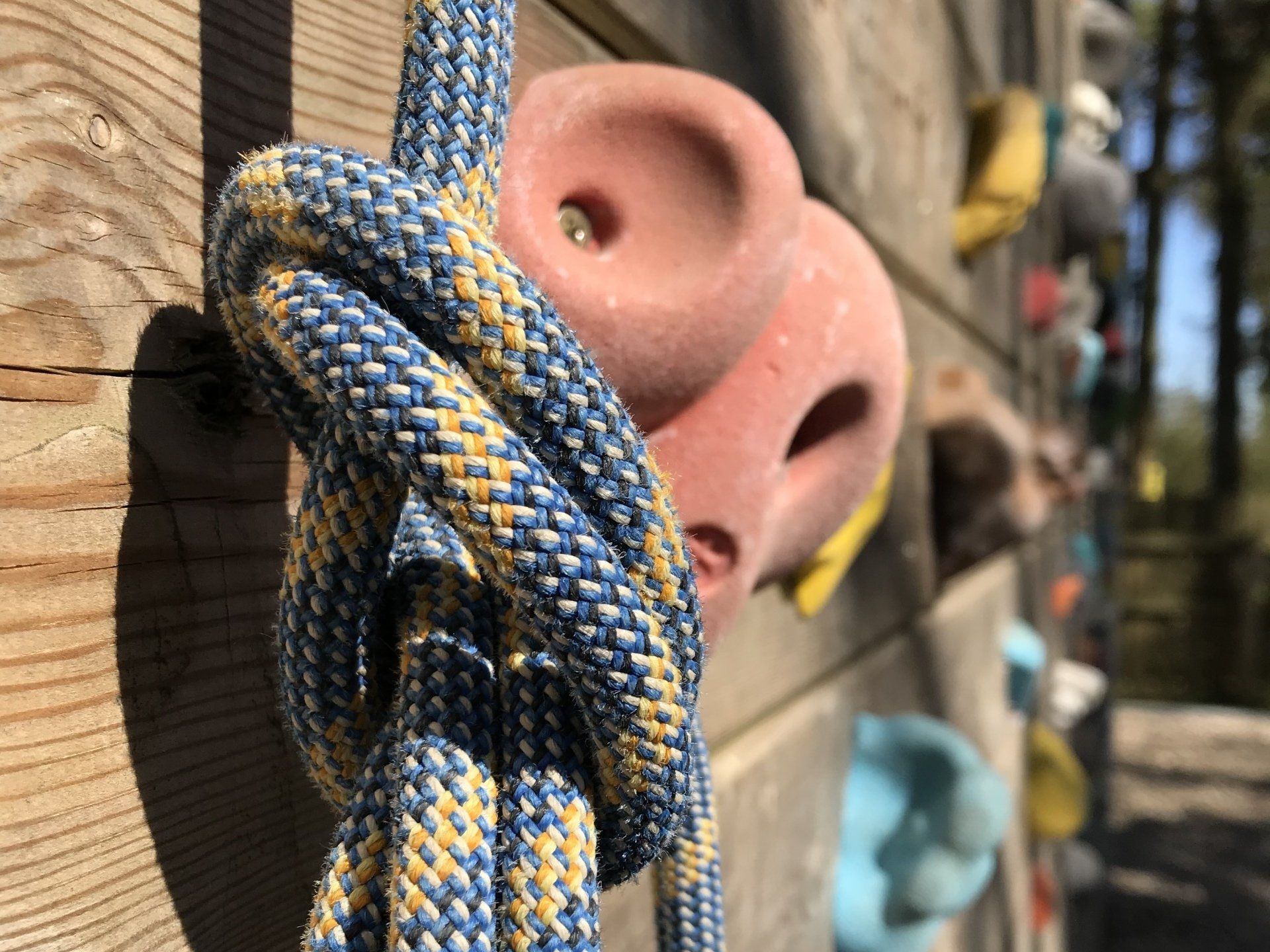A blue and yellow rope is tied to a climbing wall