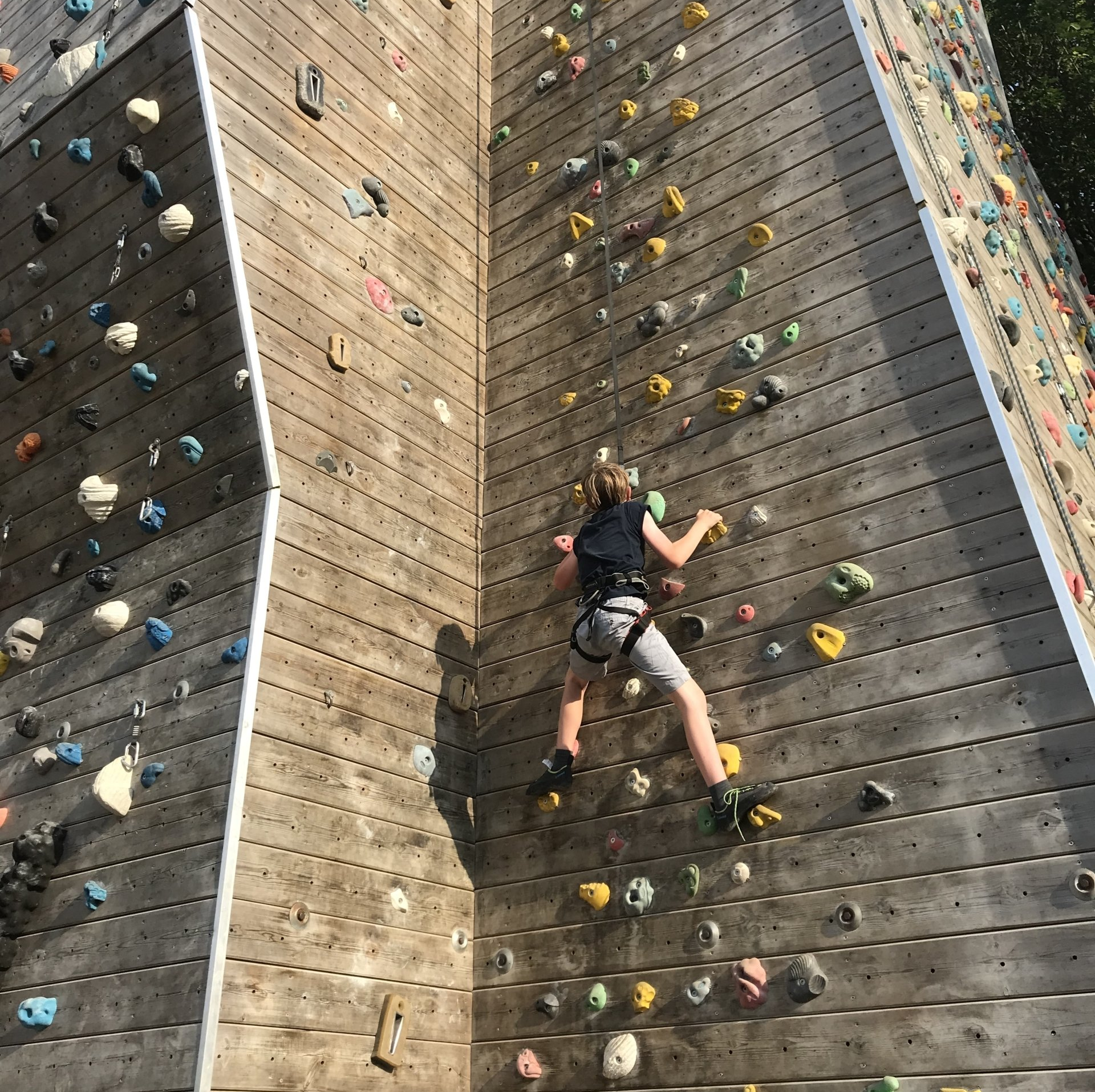 A person is climbing up a wooden climbing wall