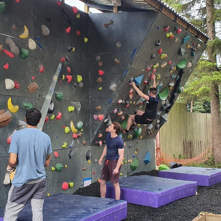 Two men are standing in front of a climbing wall