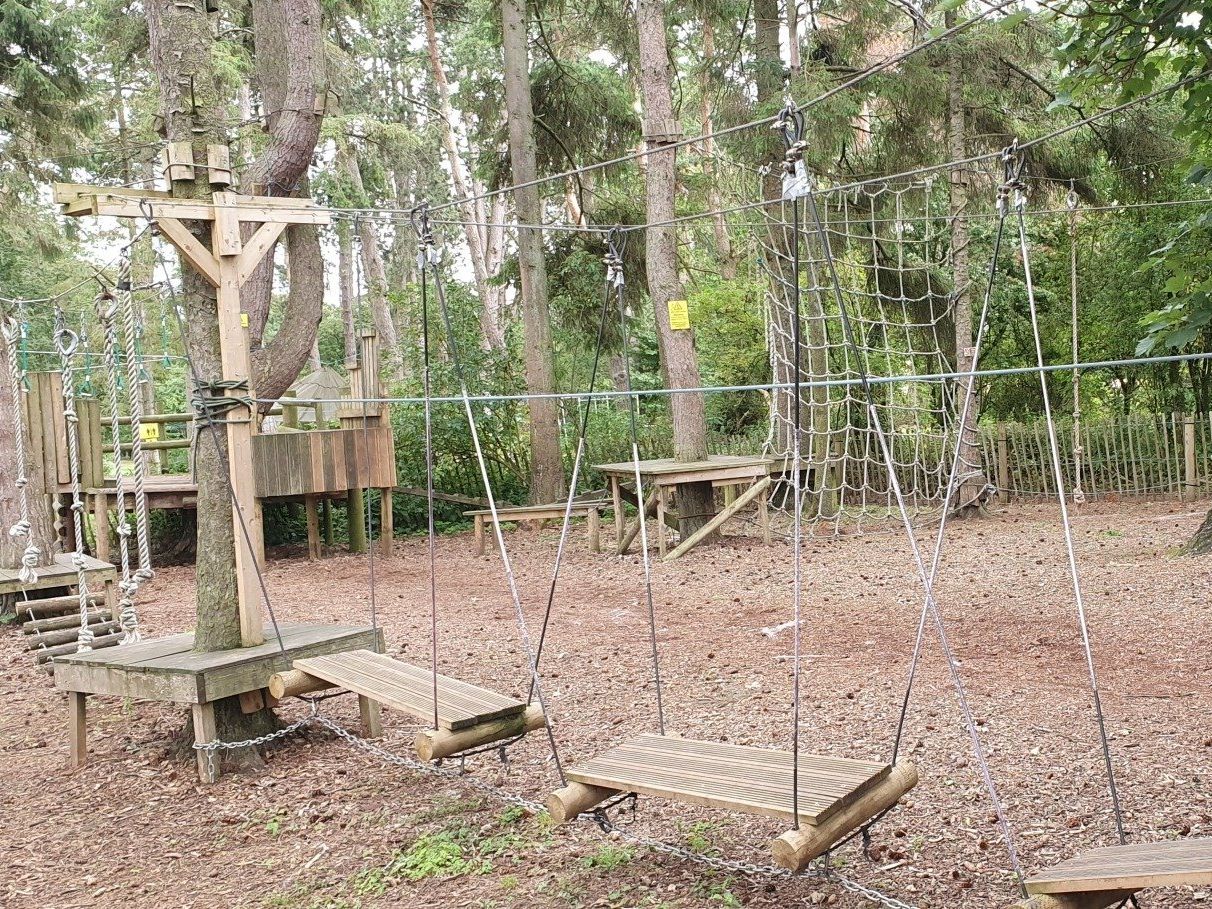 A wooden playground in the middle of a forest.