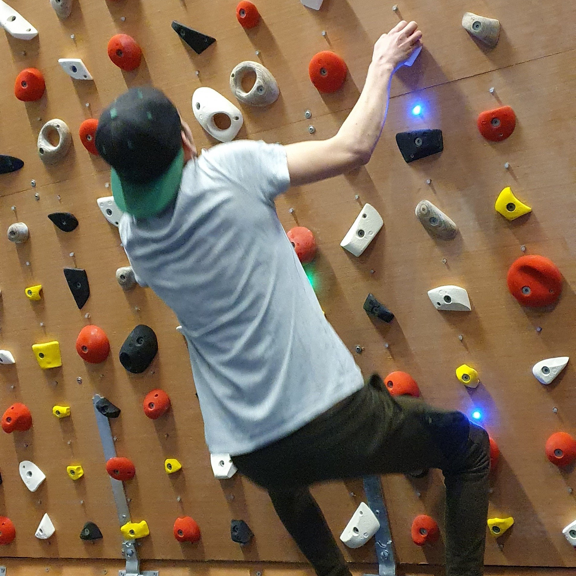 A man in a white shirt is climbing a climbing wall