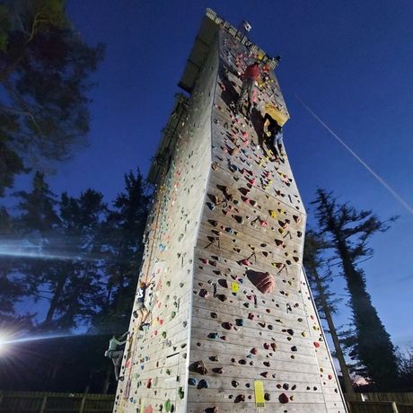 A group of people are climbing a very tall climbing wall