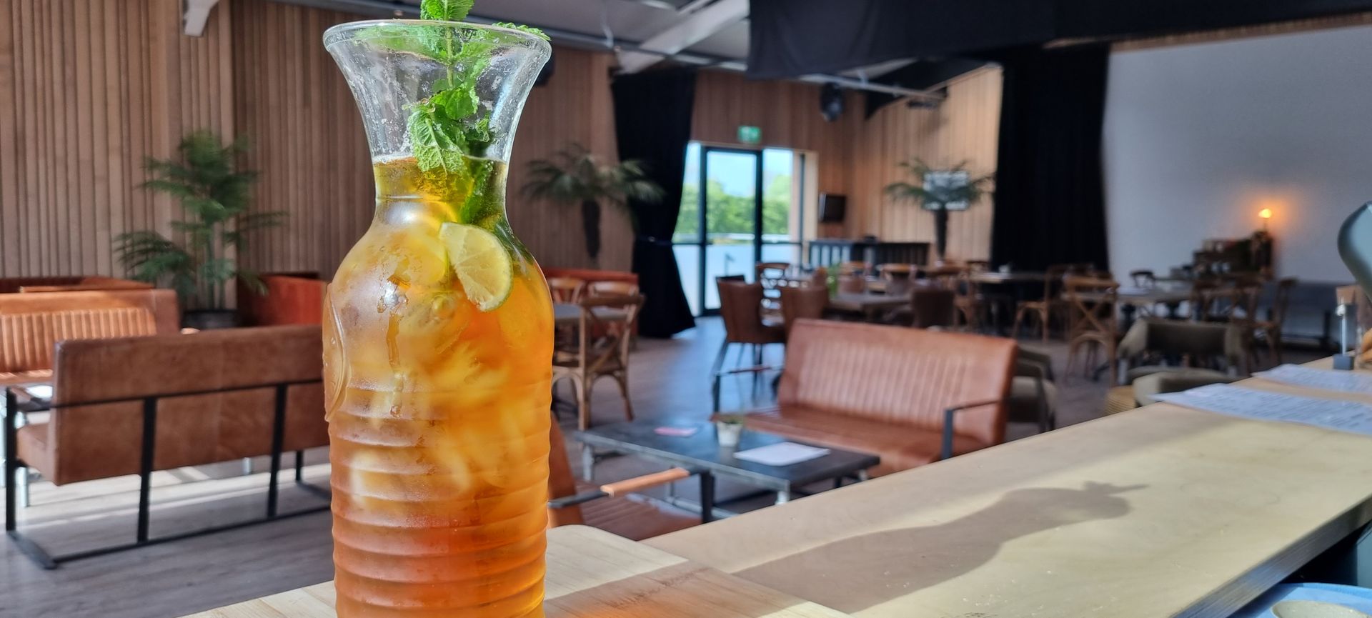 A bottle of iced tea is sitting on a table in a restaurant.