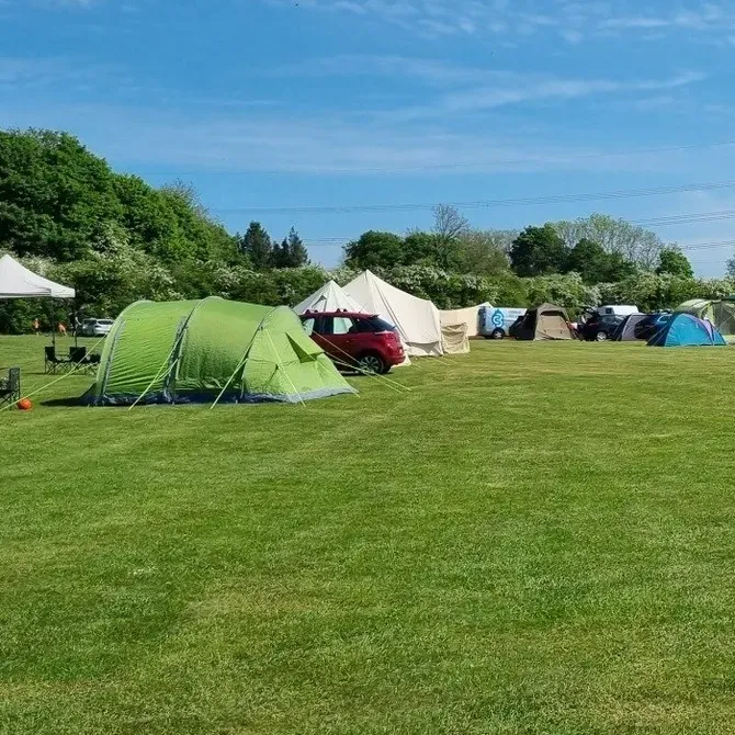 A group of tents are sitting in a grassy field.