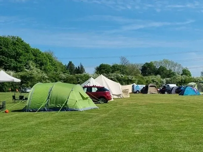 A group of tents are sitting on top of a lush green field.