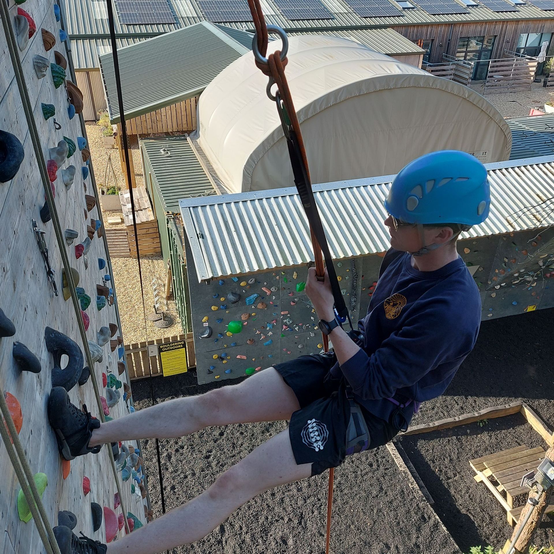 A man wearing a blue helmet is climbing a climbing wall