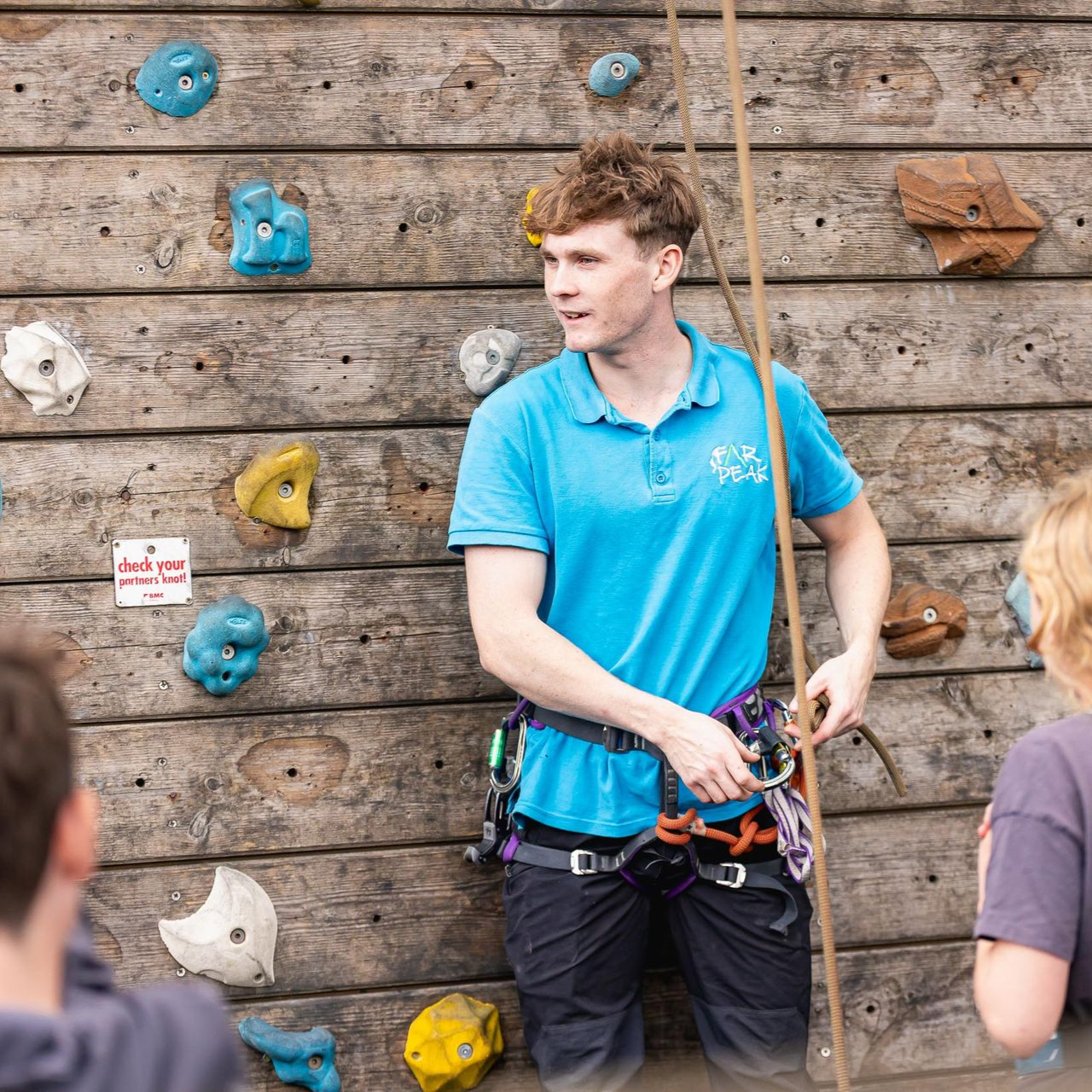 A group of people are climbing a climbing wall.