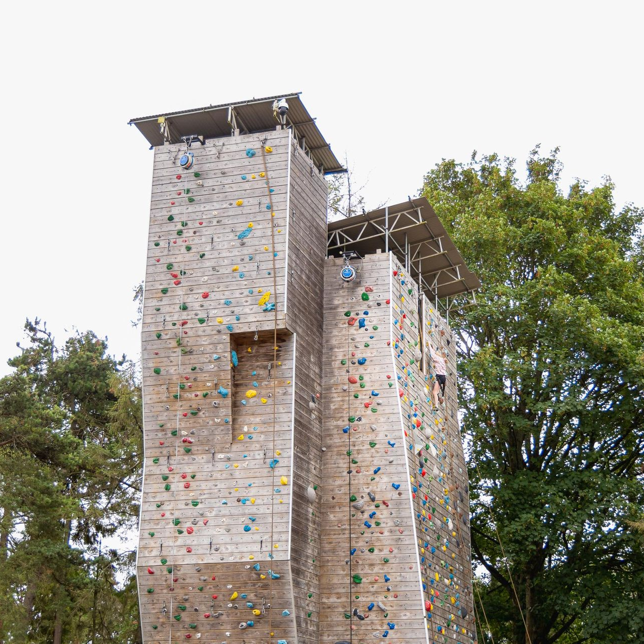 Two men are standing in front of a climbing wall