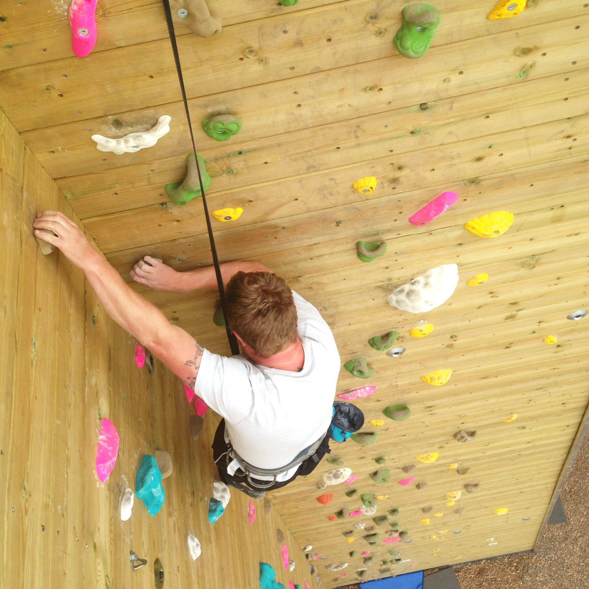 A man is climbing up a wooden climbing wall