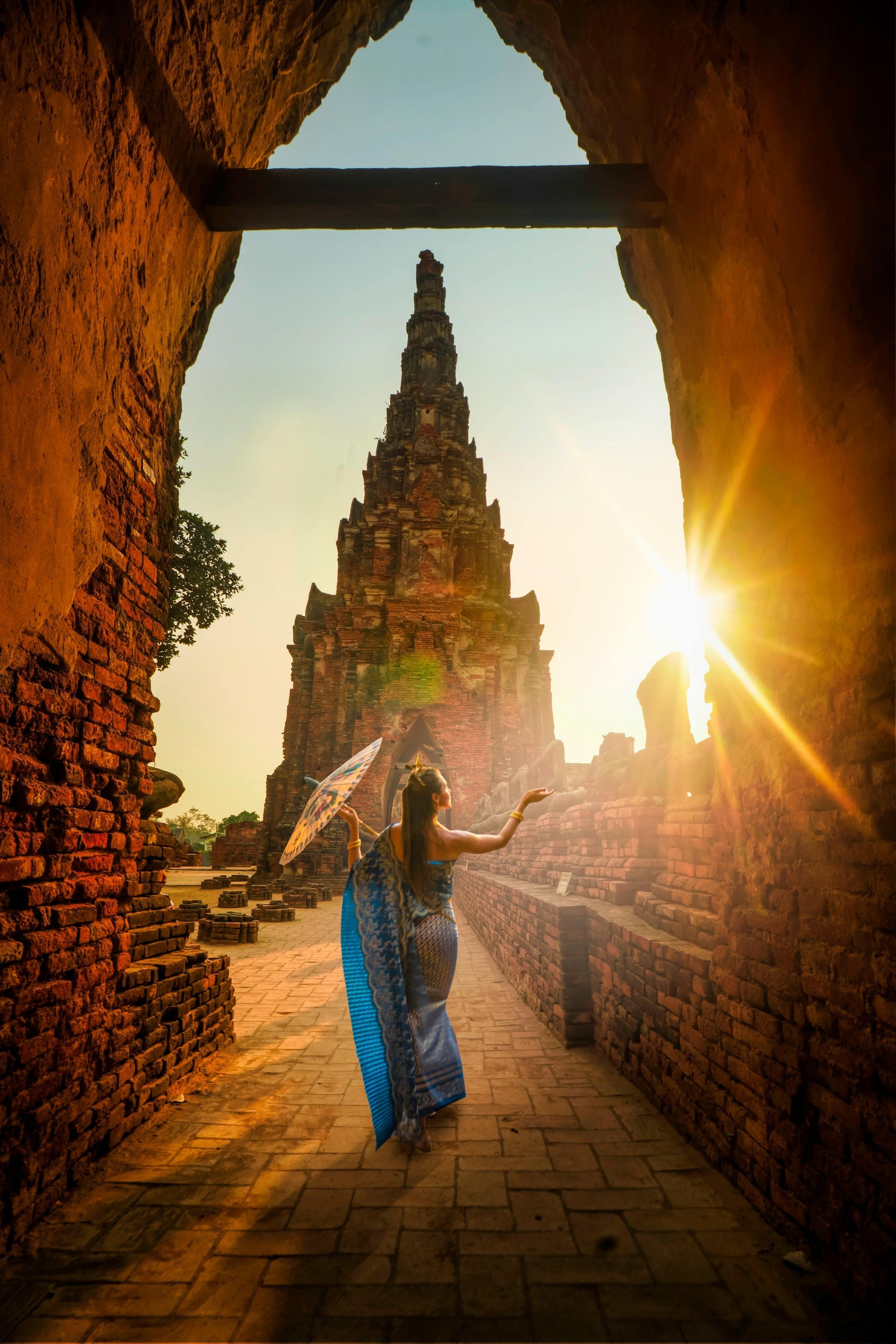 A woman is walking through a tunnel towards a temple at sunset.