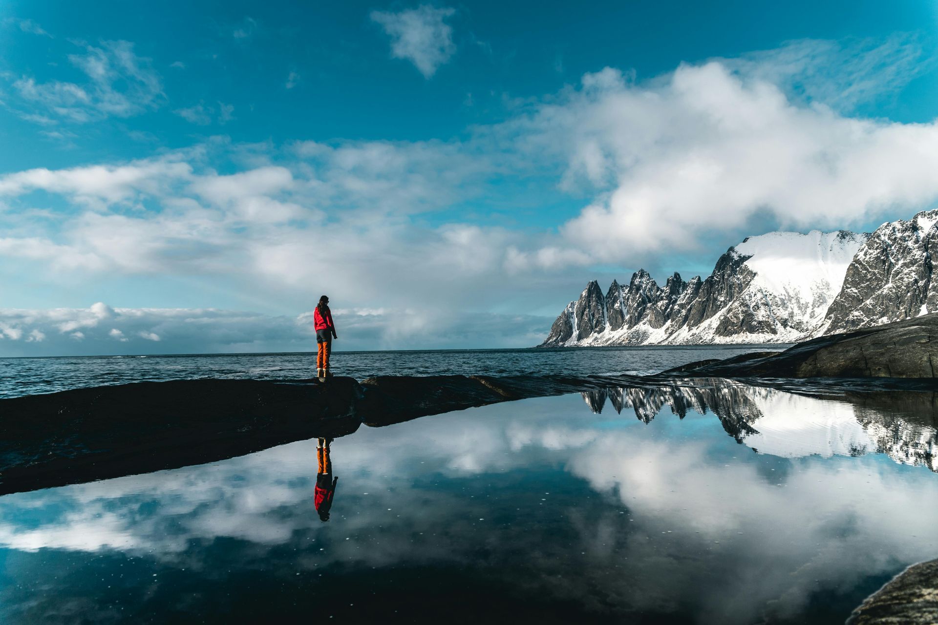 A person is standing on a cliff overlooking a body of water.