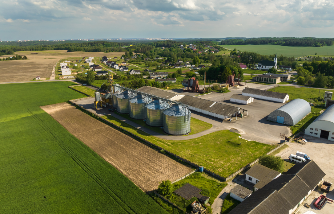 Uma vista aérea de uma fazenda com silos no meio de um campo.