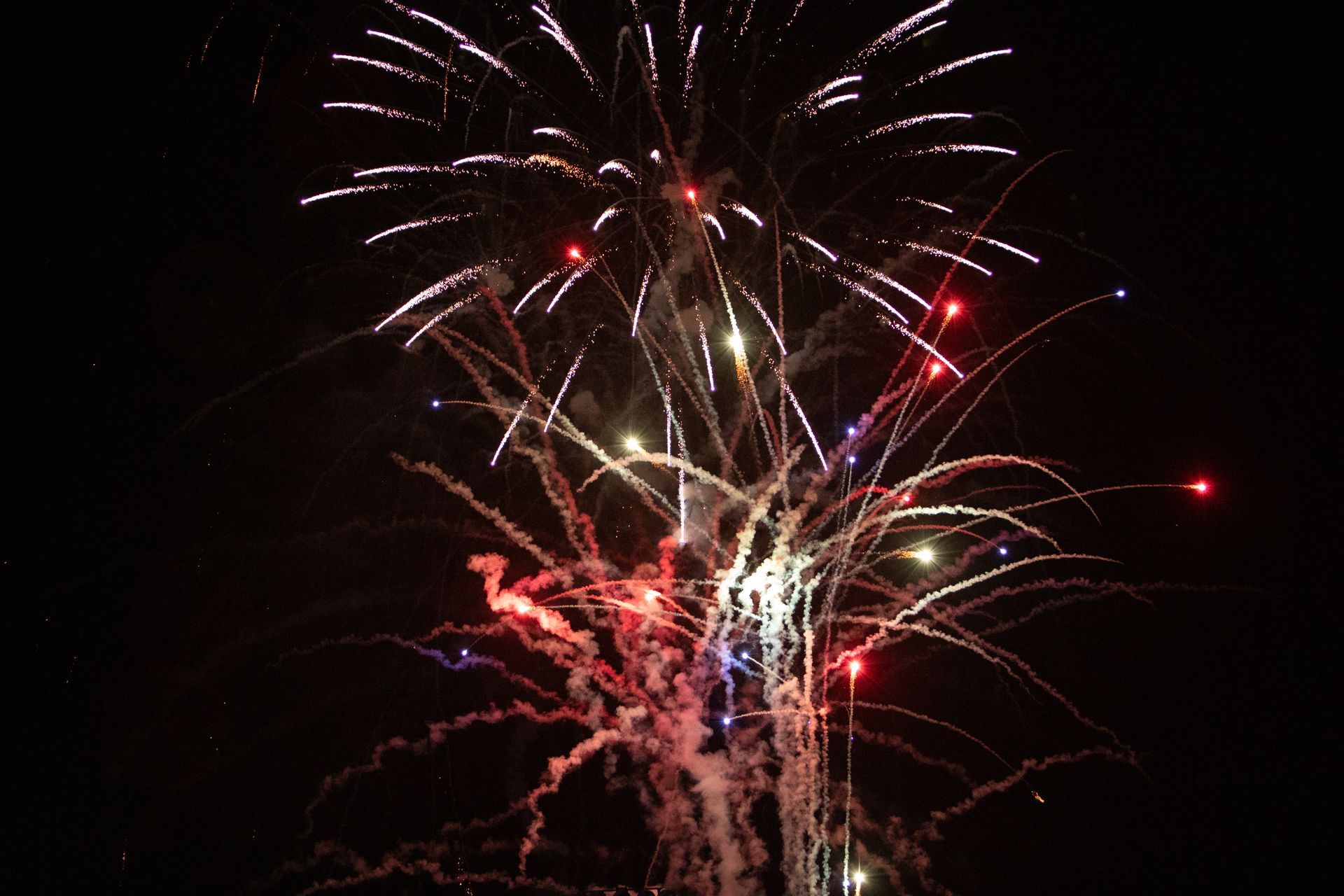 Fireworks exploding in the night sky with red, white, and blue bursts.