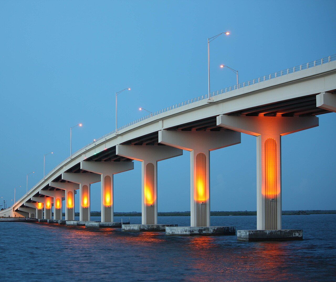 Bridge lit orange at dusk over calm water