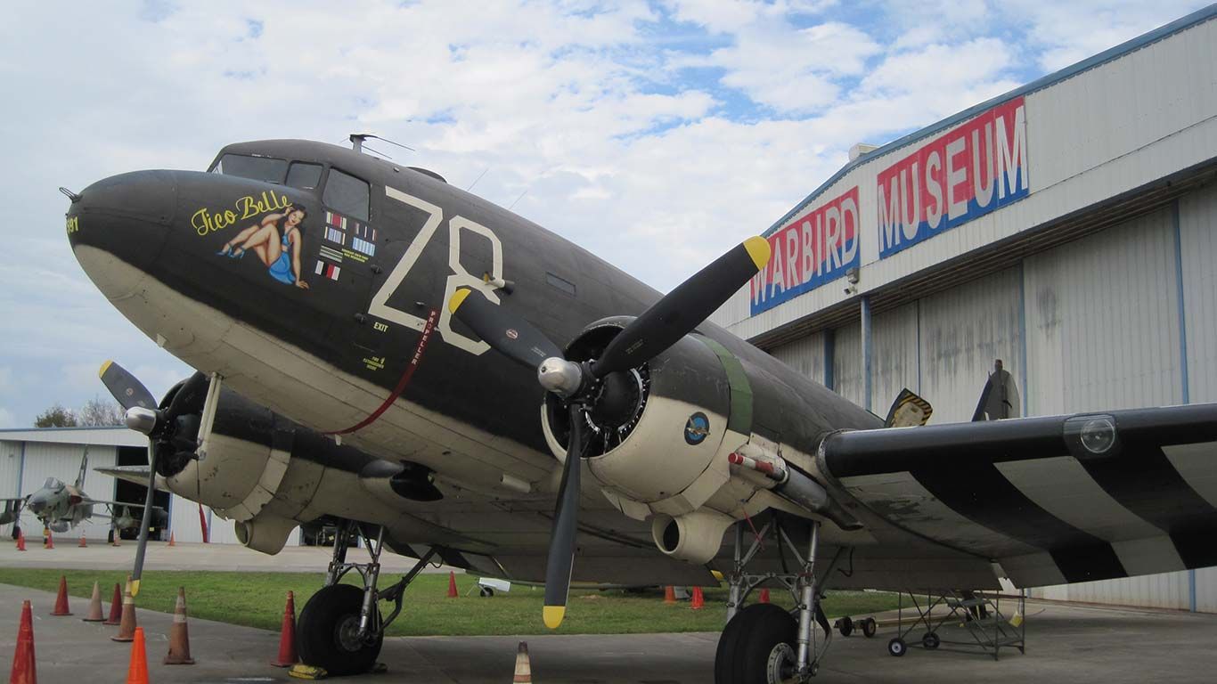 Vintage military airplane parked outside a hangar museum, black fuselage with white nose and “78” marking.
