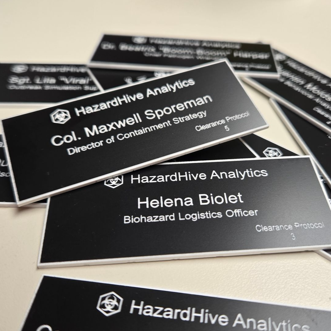 Laser engraved black and white name badges for a fictional HazardHive Analytics team.