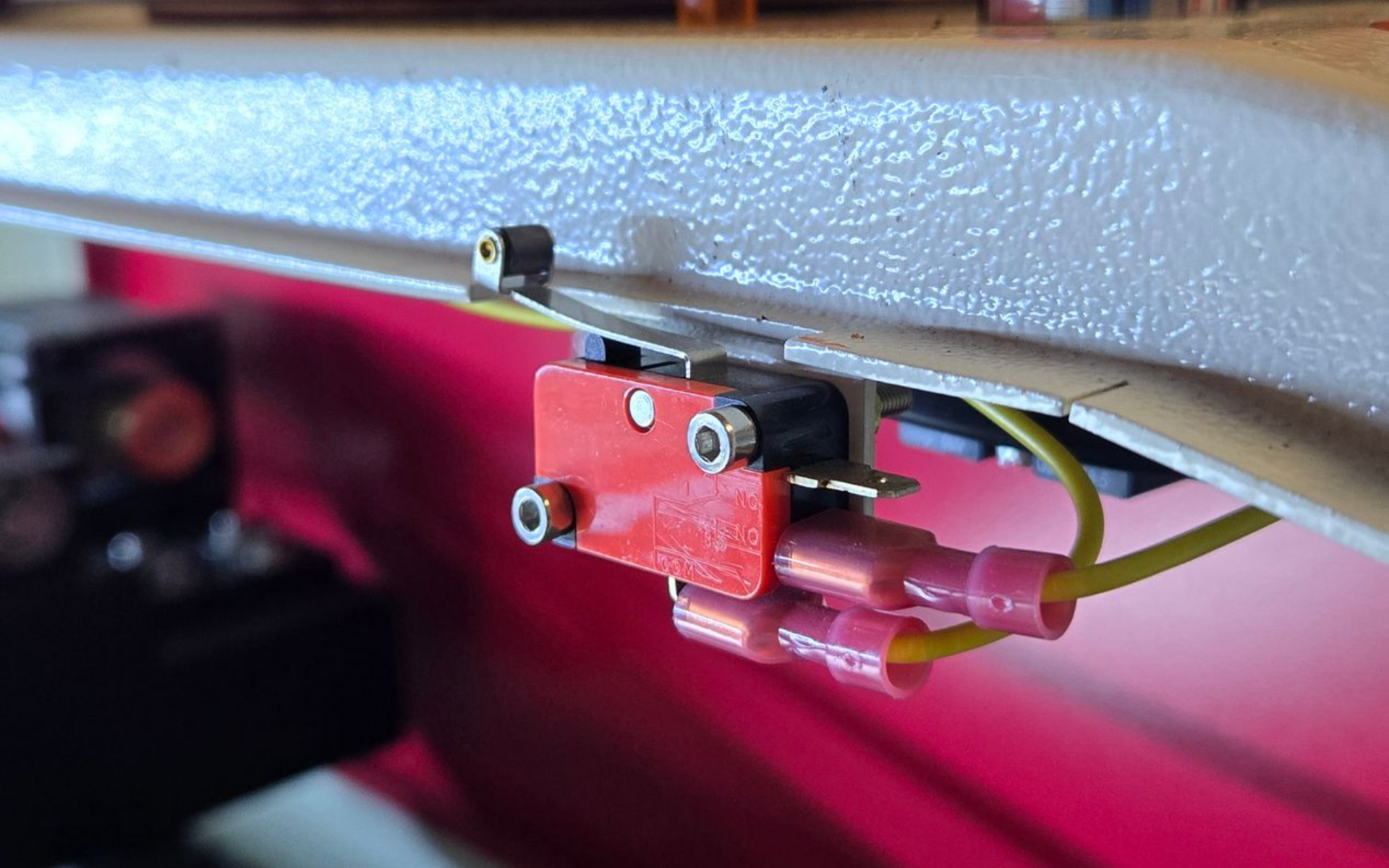 Close-up of a Rabbit Laser USA CO2 laser lid interlock switch with nearby red emergency stop button.