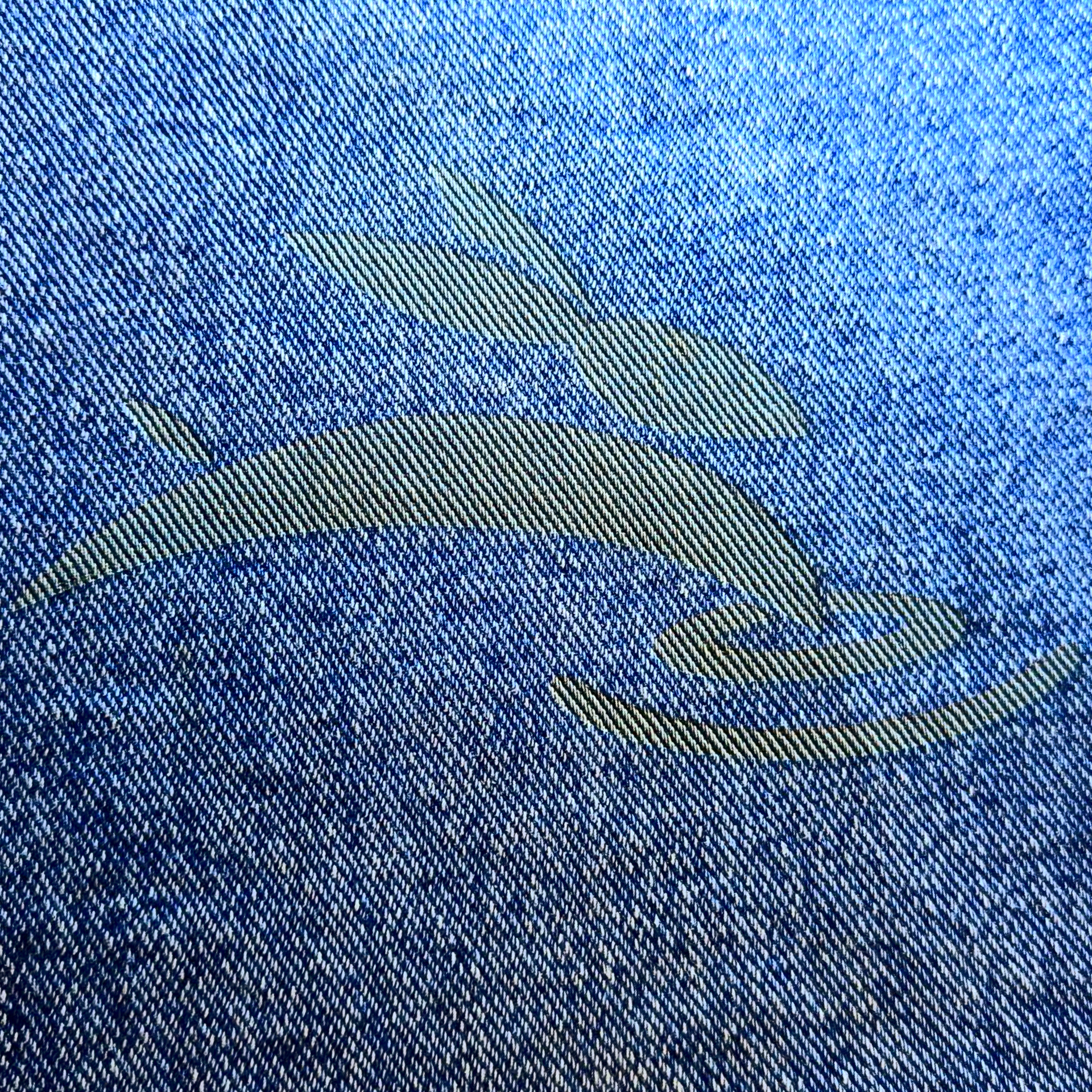 Close-up of Rabbit Laser USA logo engraved on blue denim fabric.