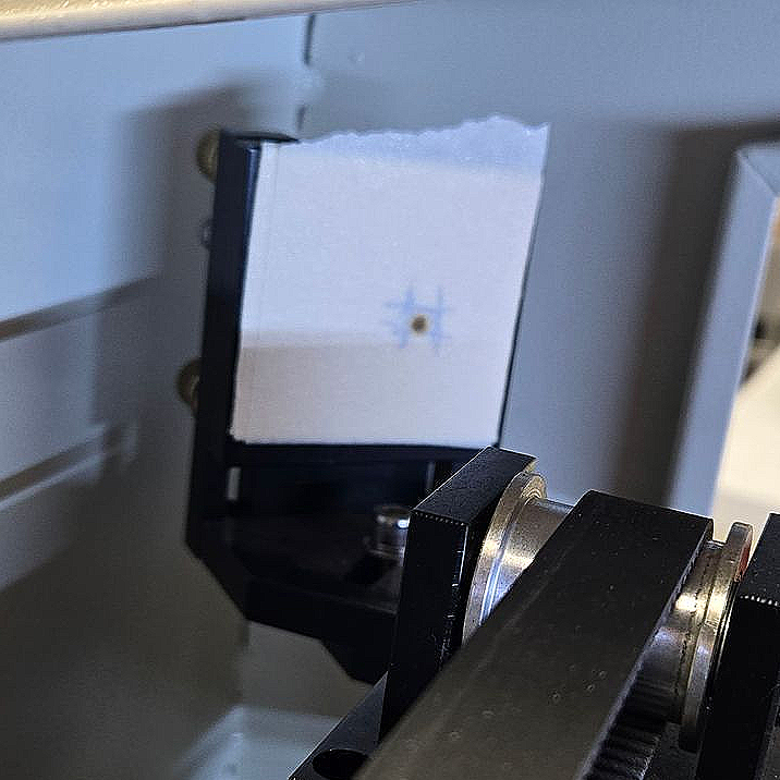 Laser beam alignment test showing burn mark centered on masking tape target