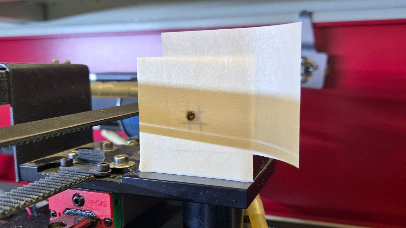 Centered laser beam burn mark on masking tape target during flying optics alignment test