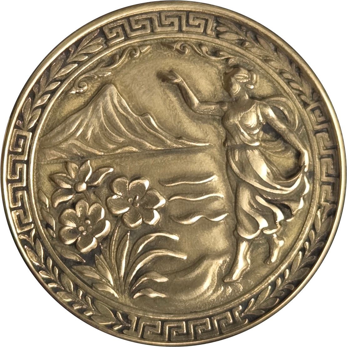 Decorative metal medallion featuring classical figure, flowers, and mountain landscape
