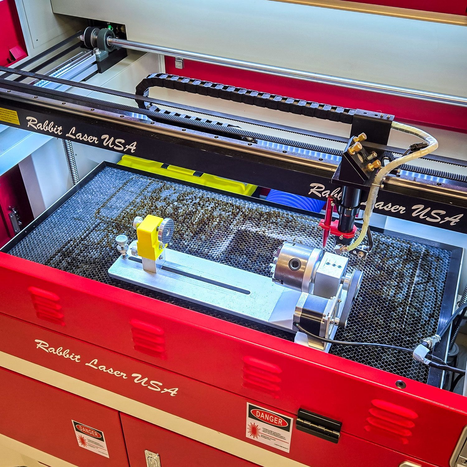 Chuck rotary attachment installed in an SD-60-9060 CO2 laser, aligned for cylindrical engraving projects.