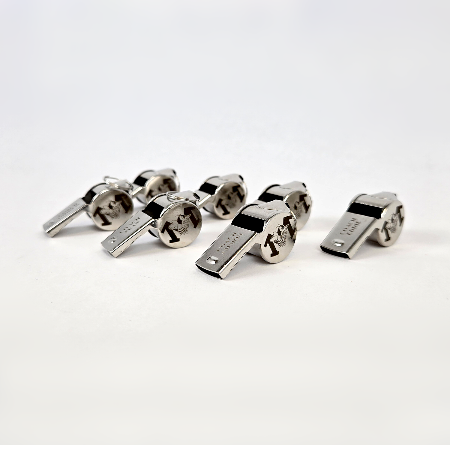 Custom engraved metal coach whistles displayed on white background