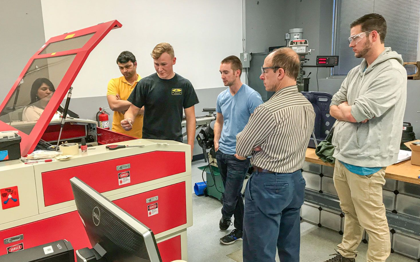 Group watching a laser machine demonstration during hands-on training.