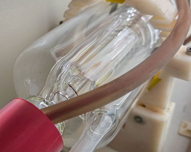 Cooling water flowing through a CO2 laser tube before startup to confirm the chiller is circulating properly.