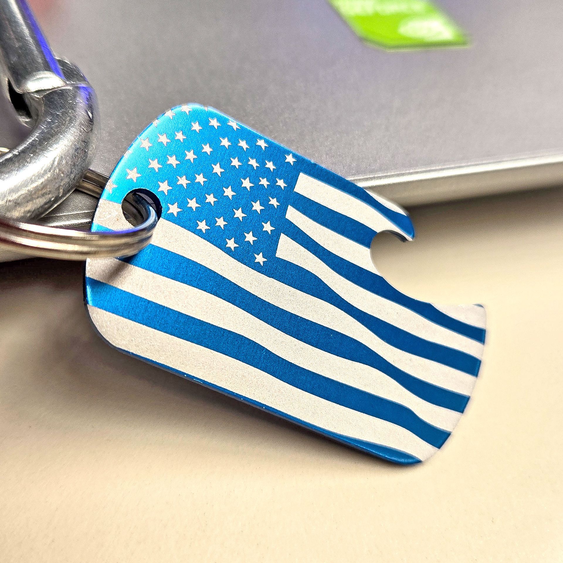 Custom keychain featuring engraved American flag design on blue anodized metal

