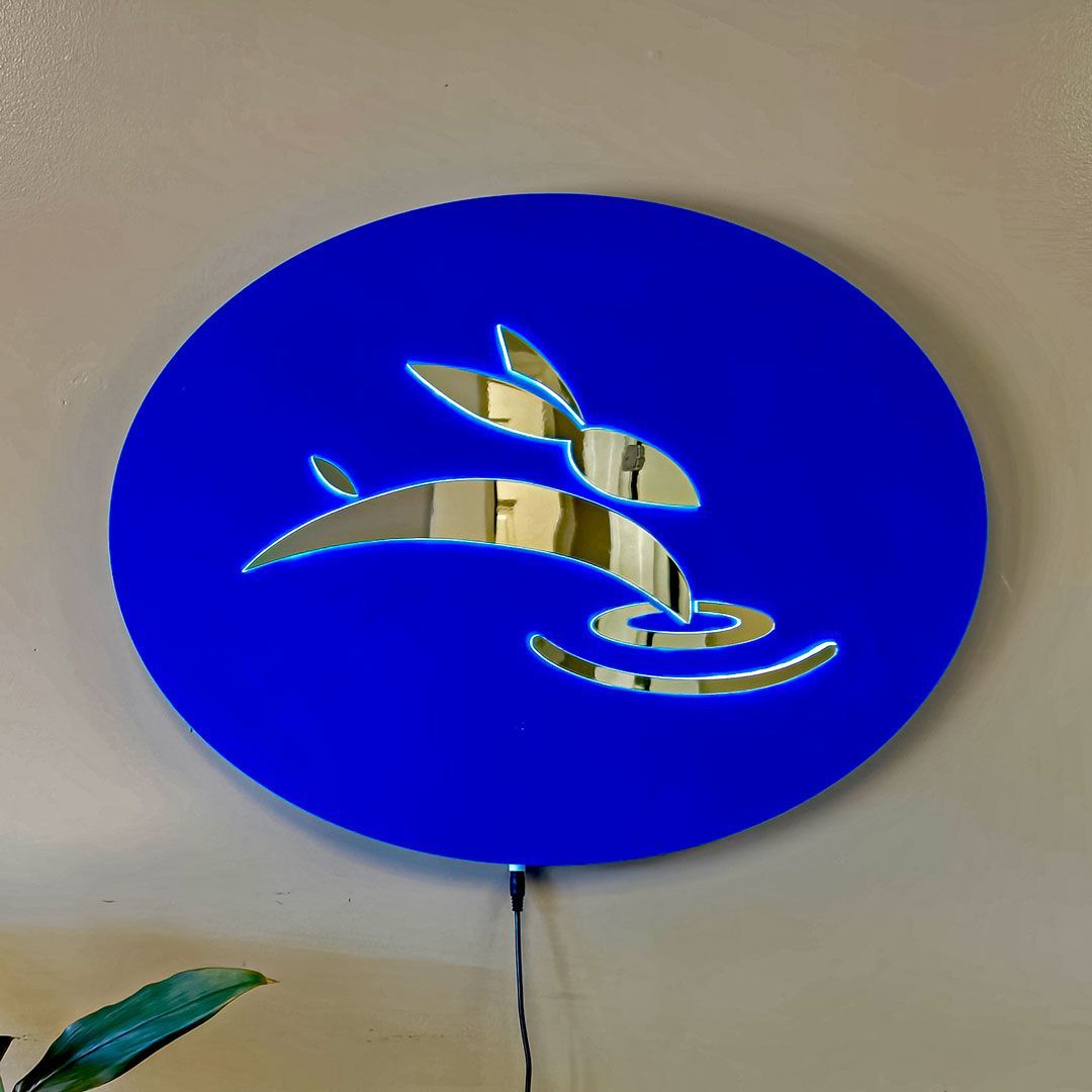 Blue backlit Rabbit Laser USA wall sign with mirrored logo cutout.
