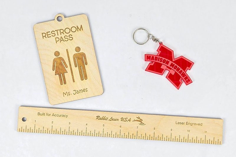 Laser engraved wood ruler, restroom pass tag, and acrylic keychain on white background
