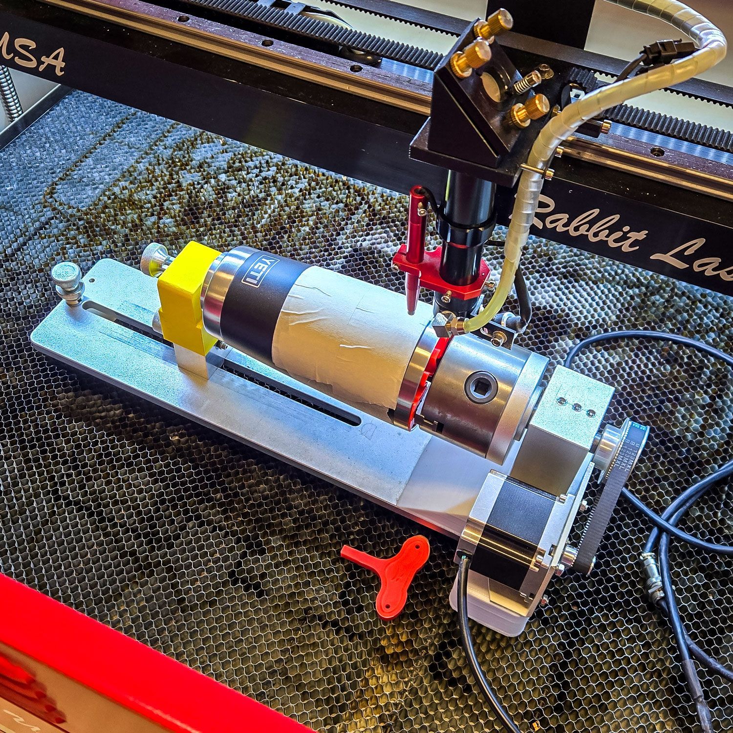 YETI tumbler covered with masking tape in a chuck rotary for low-power calibration testing.