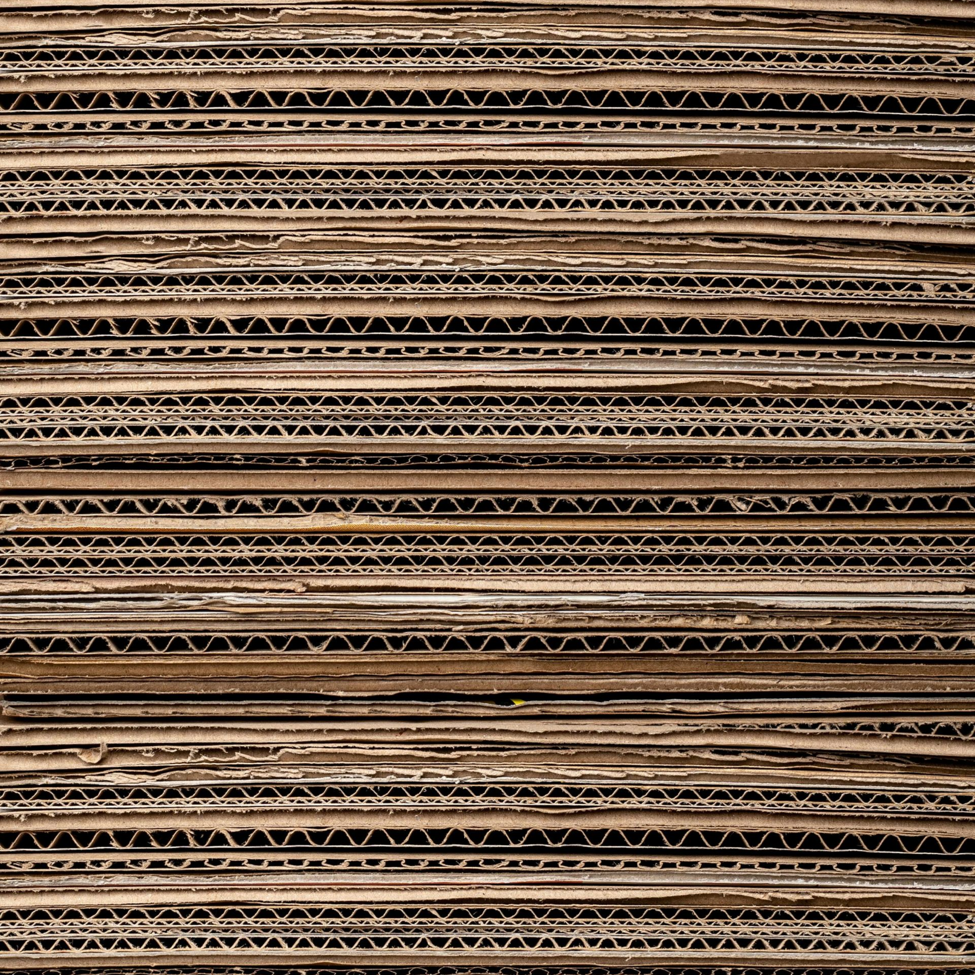 Stacked corrugated cardboard sheets showing layered fluted edges.