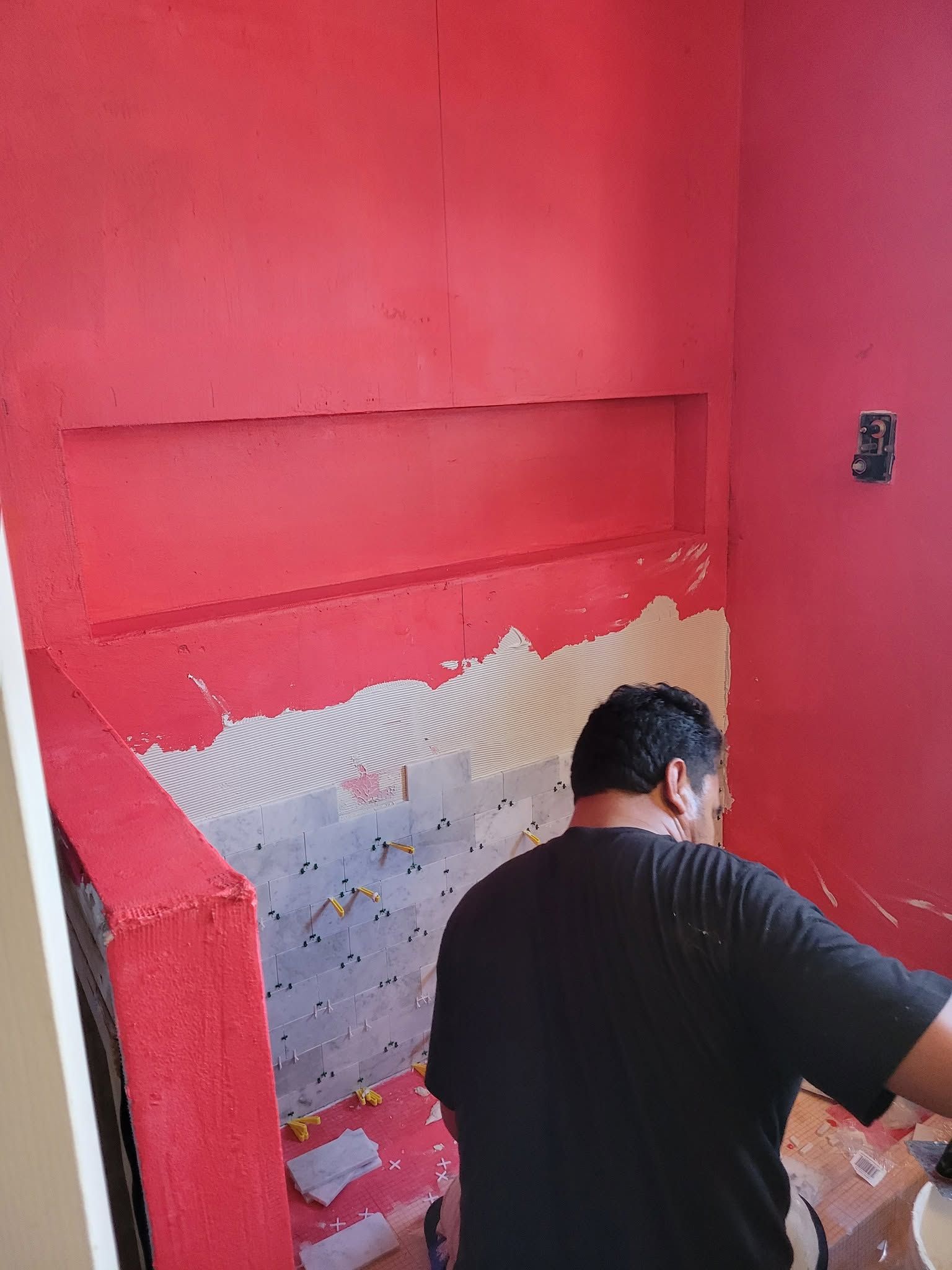 Person painting a red wall and patching a damaged section in an indoor staircase area
