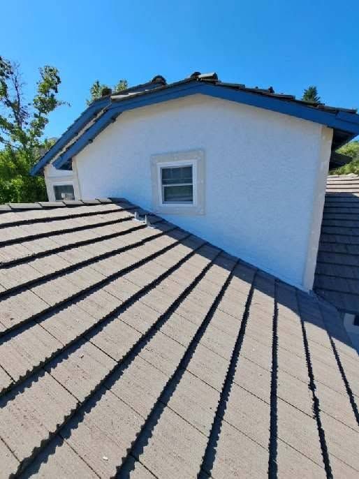 Roofing underlayment on a house roof beside a white dormer and blue sky