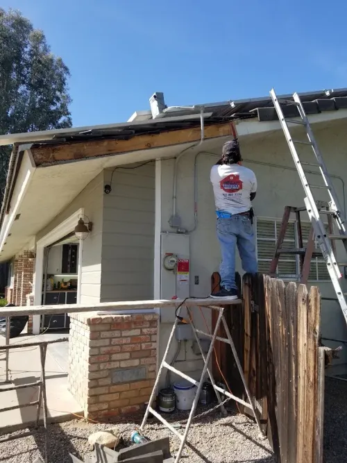 Worker on ladder repairing roof gutter on a house exterior