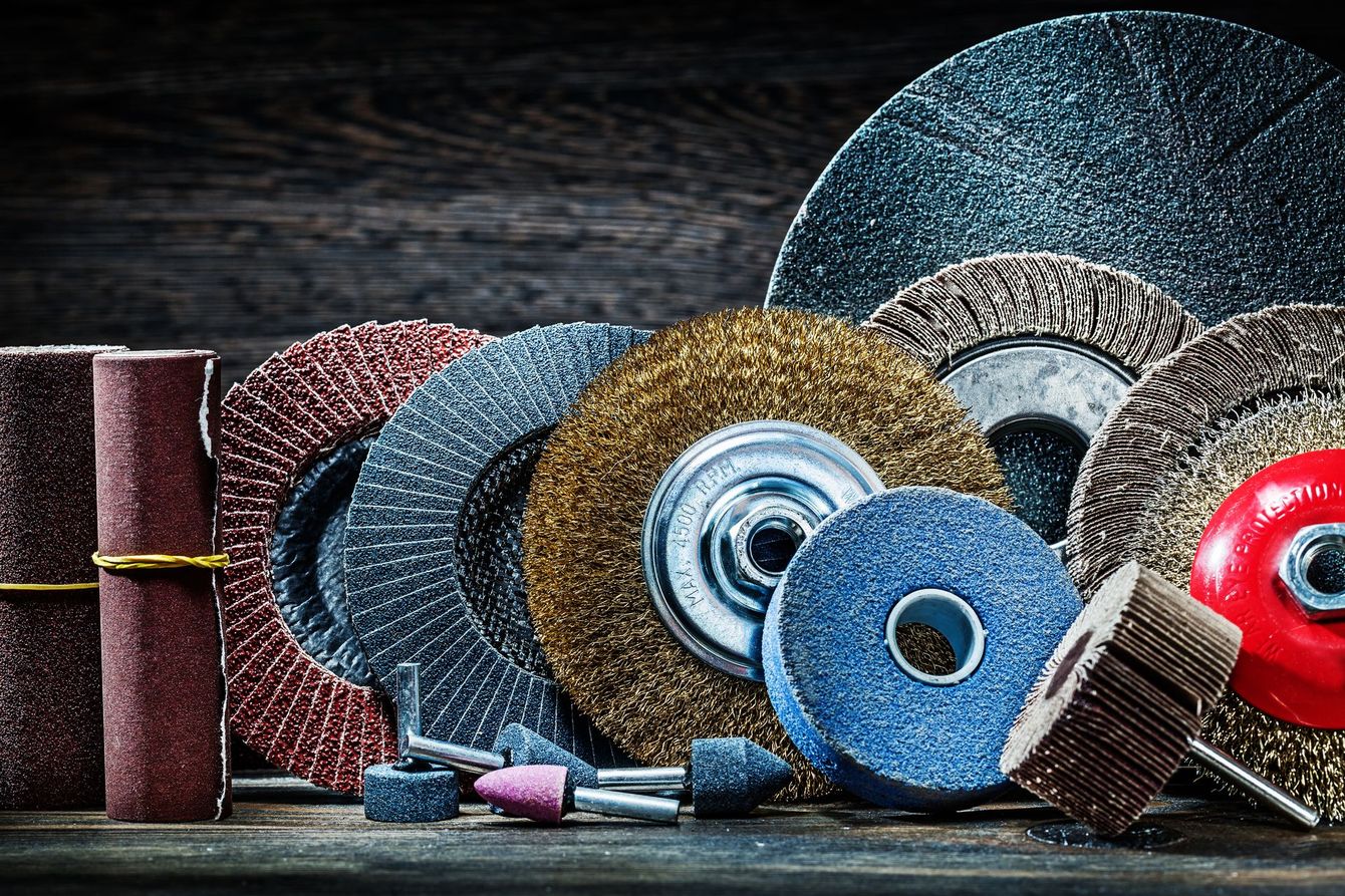 Assortiti dischi abrasivi e mole abrasive disposti su una superficie di legno scuro