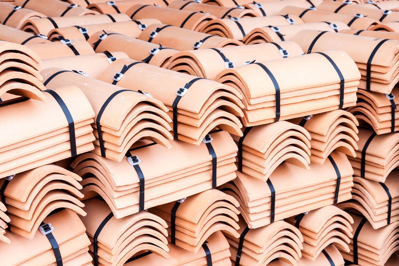 Pile di tegole di terracotta legate con cinghie scure in un magazzino