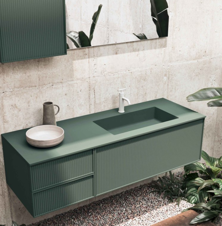 Mobile bagno color verde salvia con lavabo integrato, lavabo rotondo e specchio, su una parete in pietra chiara.