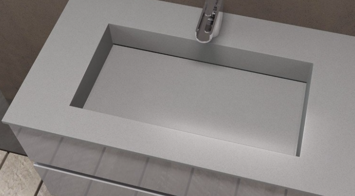 Lavabo rettangolare bianco con rubinetto cromato in un'area del piano del bagno piastrellata.